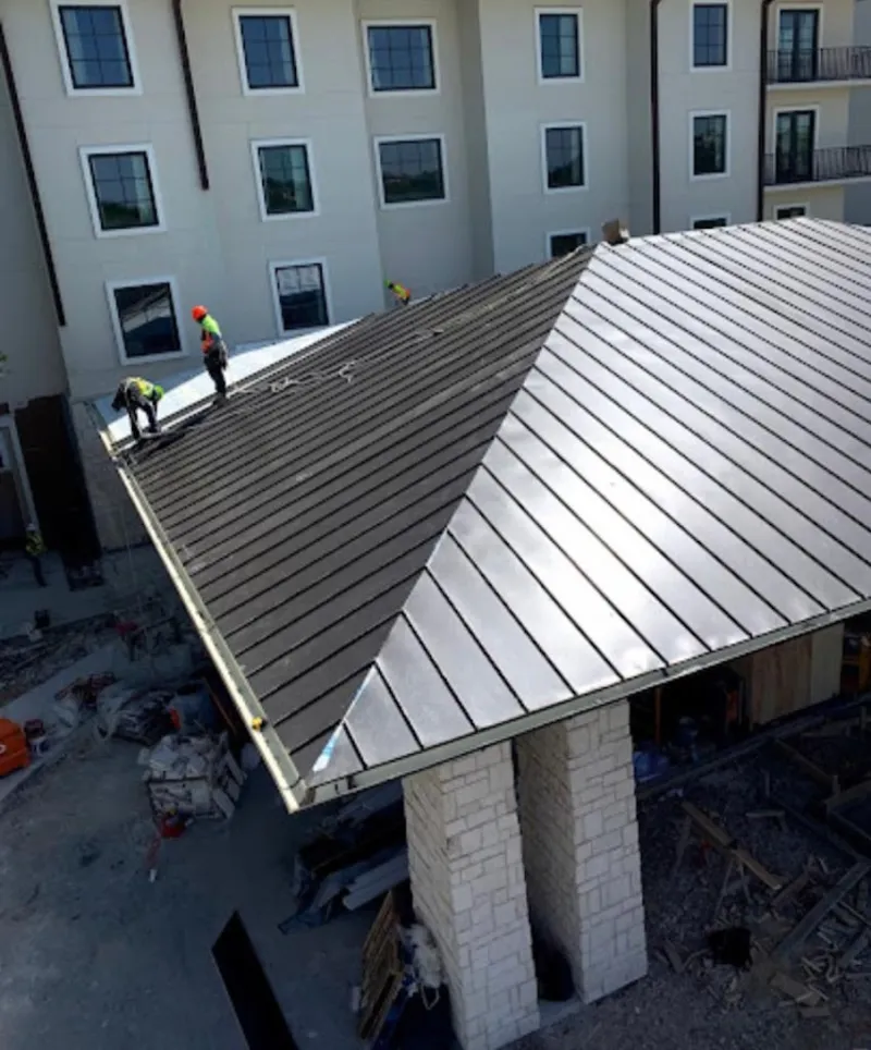 Crew installing standing seam metal roof panels on a commercial project in South Heidelberg